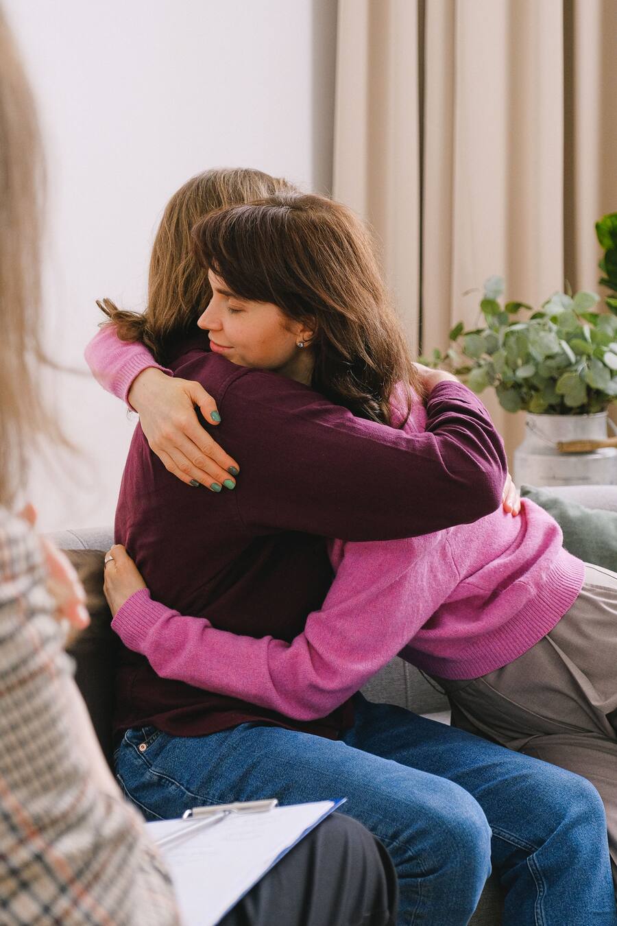 Mãe e filho se abraçando durante uma conversa com uma profissional